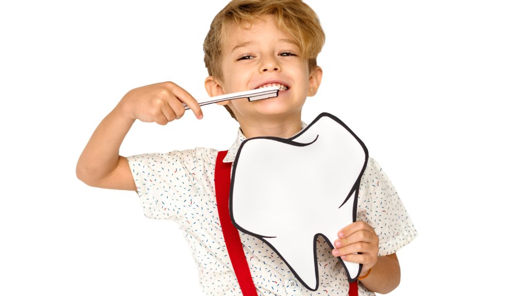 Büyük bir diş figürü tutan mutlu ve gülümseyen çocuk, sağlıklı diş fırçalama alışkanlıklarını teşvik ediyor.